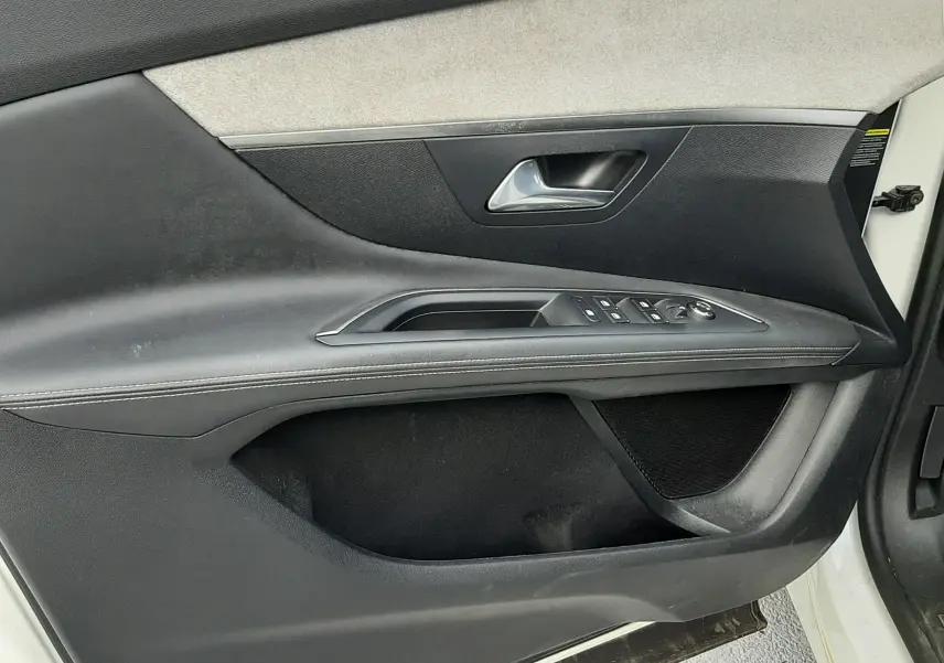 Vue intérieure côté gauche de la porte avant d'un Peugeot 3008 blanc nacré avec garniture noire et beige, commandes de vitres visibles.