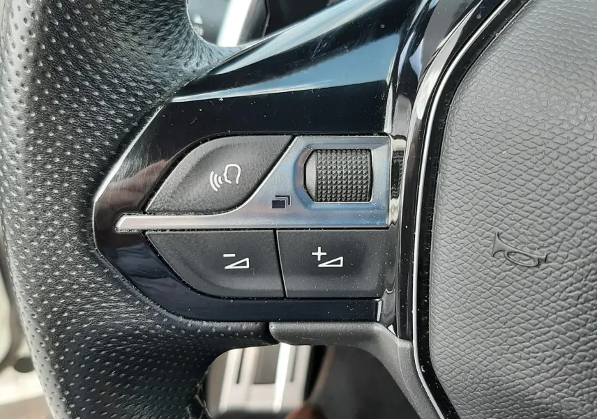Gros plan sur les commandes gauche du volant en cuir perforé du Peugeot 3008 2022, finition noire brillante.
