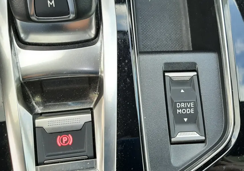 Gros plan sur la console centrale noire du Peugeot 3008 2022, avec bouton Drive Mode et frein à main électronique.