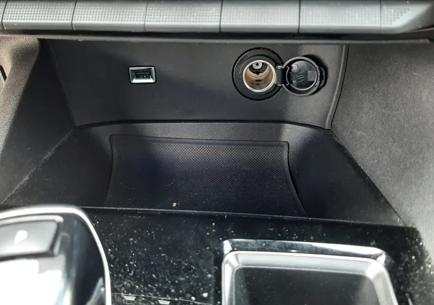 Vue rapprochée de la console centrale noire du Peugeot 3008 2022, montrant prise USB et allume-cigare ouverts.
