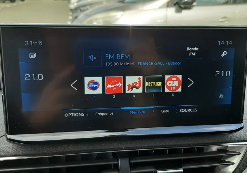 Écran tactile central du Peugeot 3008 2022 affichant les stations radio FM, avec tableau de bord noir et aérateurs dessous.