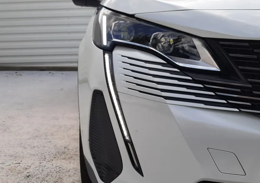 Gros plan sur l'avant droit du Peugeot 3008 blanc nacré avec feux LED et détails noirs contrastants.