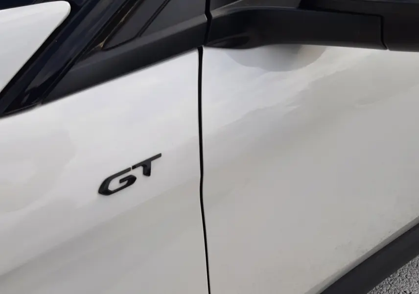 Détail du logo GT sur la porte avant gauche d’un Peugeot 3008 blanc nacré avec toit noir.