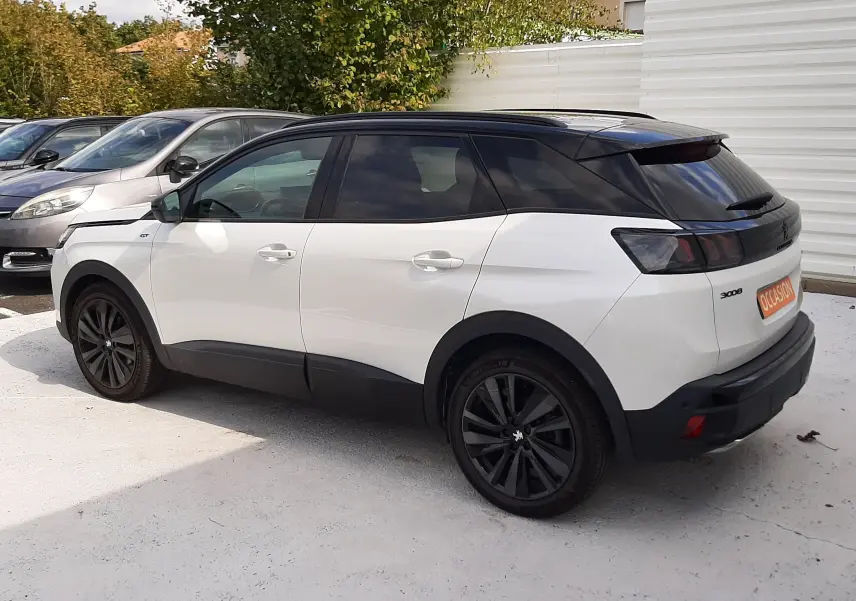 Peugeot 3008 blanc nacré avec toit noir, vue 3/4 arrière droit, jantes noires et vitres teintées.