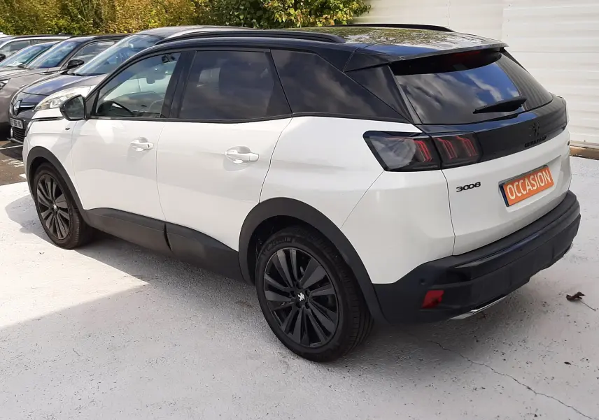 Peugeot 3008 blanc nacré avec toit noir, vue 3/4 arrière droit, jantes noires et feux arrière LED distinctifs.