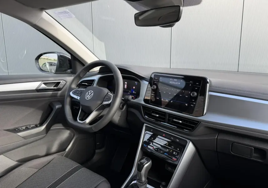 Vue intérieure côté conducteur du Volkswagen T-Roc 1.5 TSI 150 DSG Life 30 Years avec tableau de bord moderne et écran tactile.