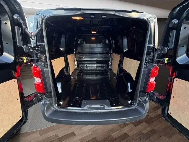 Vue arrière ouverte du Citroën Jumpy noir montrant l’espace de chargement avec cloison pleine et portes battantes ouvertes.