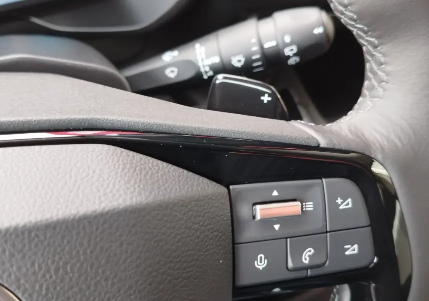 Gros plan sur les commandes noires du volant en cuir gris du Citroën Berlingo 2025, avec molette et boutons multifonctions.