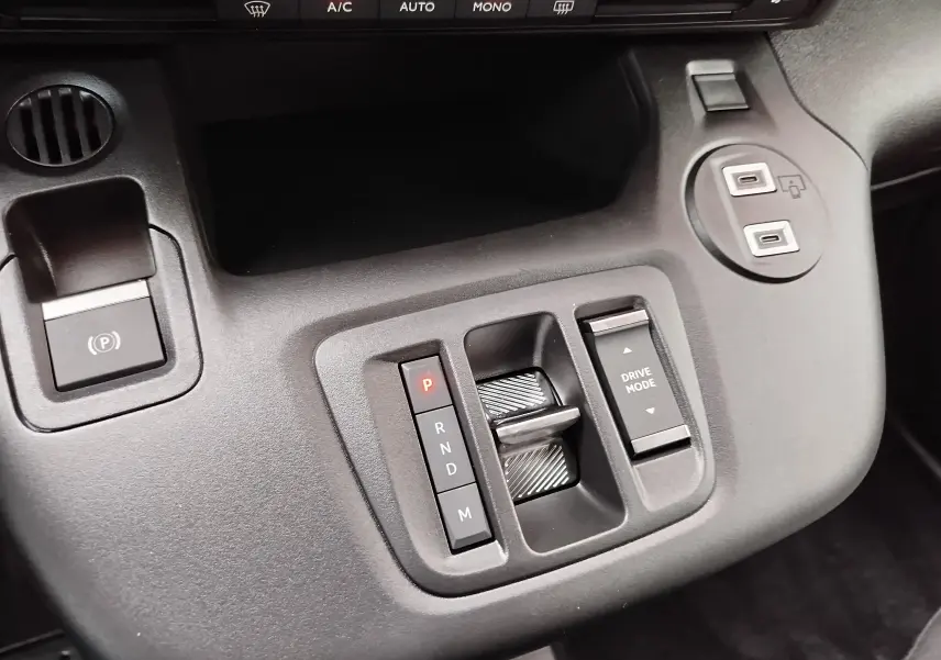 Gros plan sur la console centrale noire du Citroën Berlingo 2025 montrant la commande de boîte auto et le bouton Drive Mode.