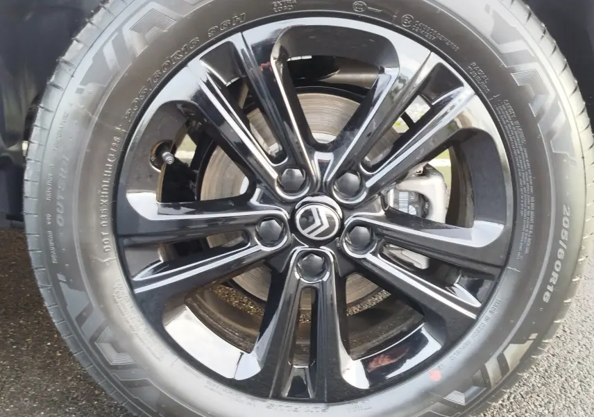 Gros plan sur la jante noire brillante de la roue avant droite du Citroën Berlingo Kaolin White 2025.