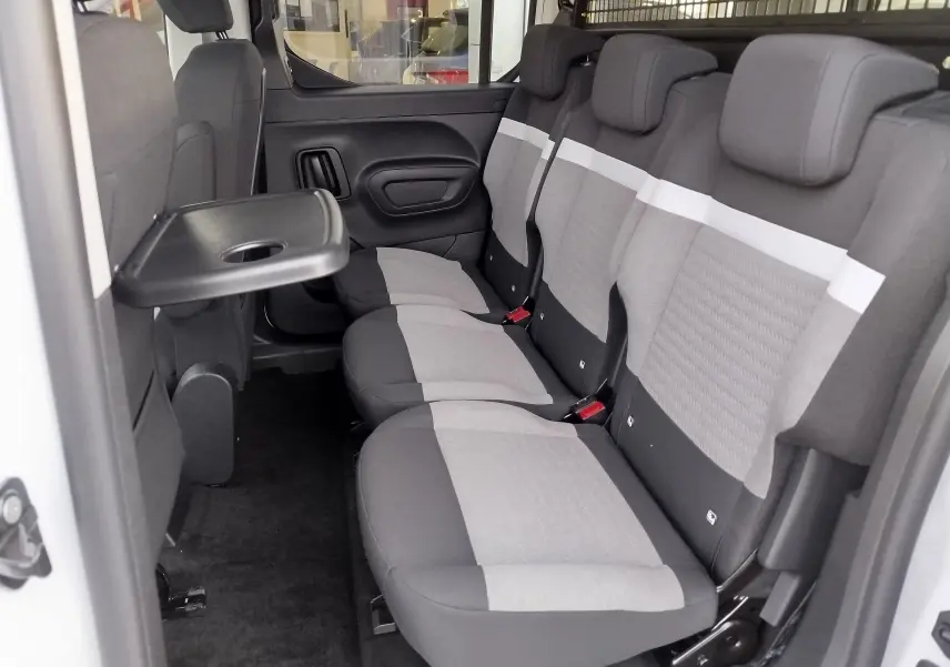 Vue intérieure côté droit du Citroën Berlingo 2025 Kaolin White, montrant la banquette arrière grise avec tablette rabattable.