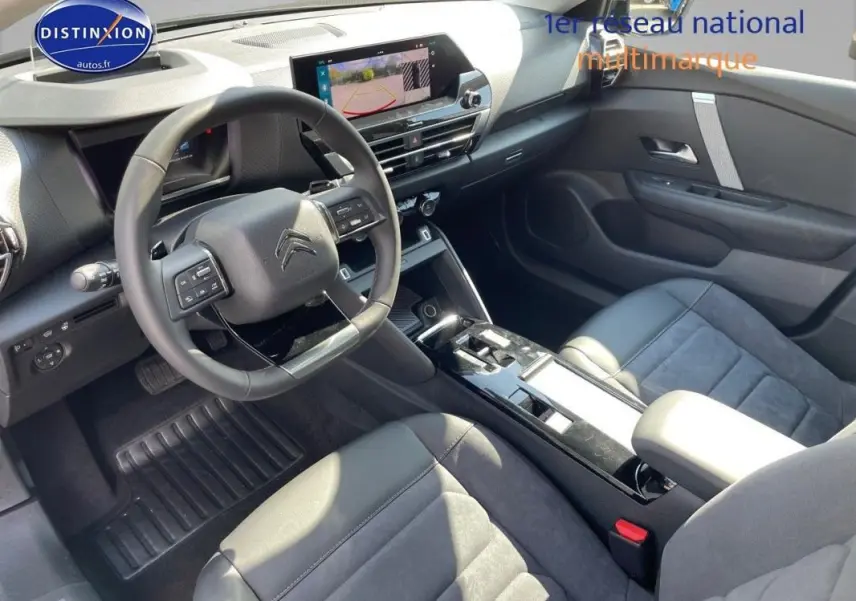 Vue intérieure côté conducteur de la Citroën C4 2024, tableau de bord moderne avec écran tactile et volant cuir noir.