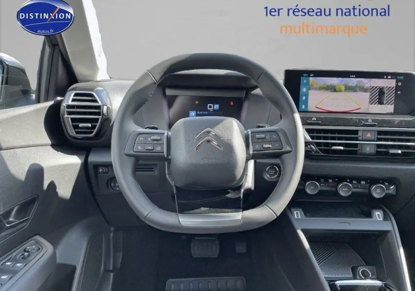 Vue intérieure centrée sur le volant cuir de la Citroën C4 2024 avec écran tactile et caméra de recul affichée.