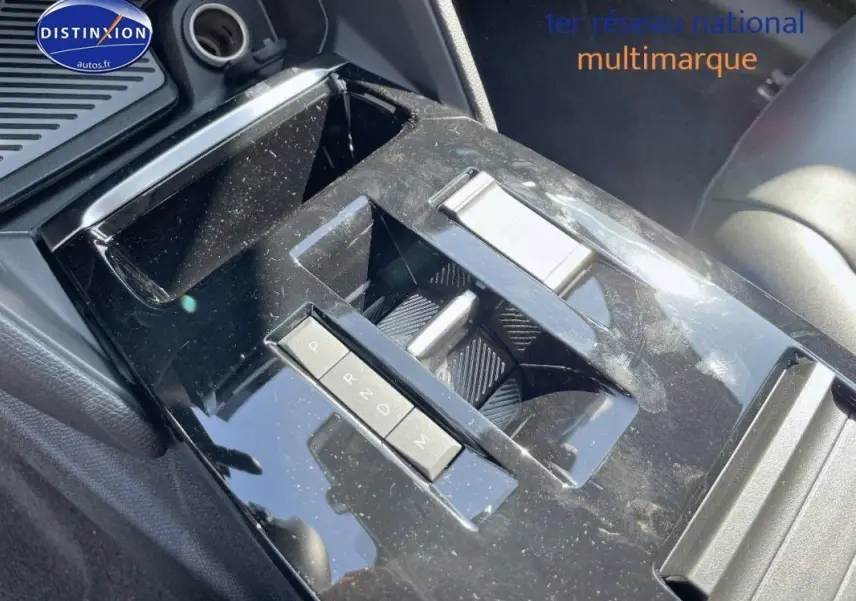 Gros plan sur la console centrale noire brillante de la Citroën C4 2024 avec commandes de boîte automatique et rangement.