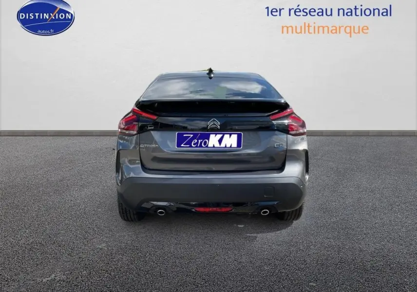 Vue arrière d'une Citroën C4 platine 2024 avec feux LED et double sortie d'échappement visible sur sol goudronné.