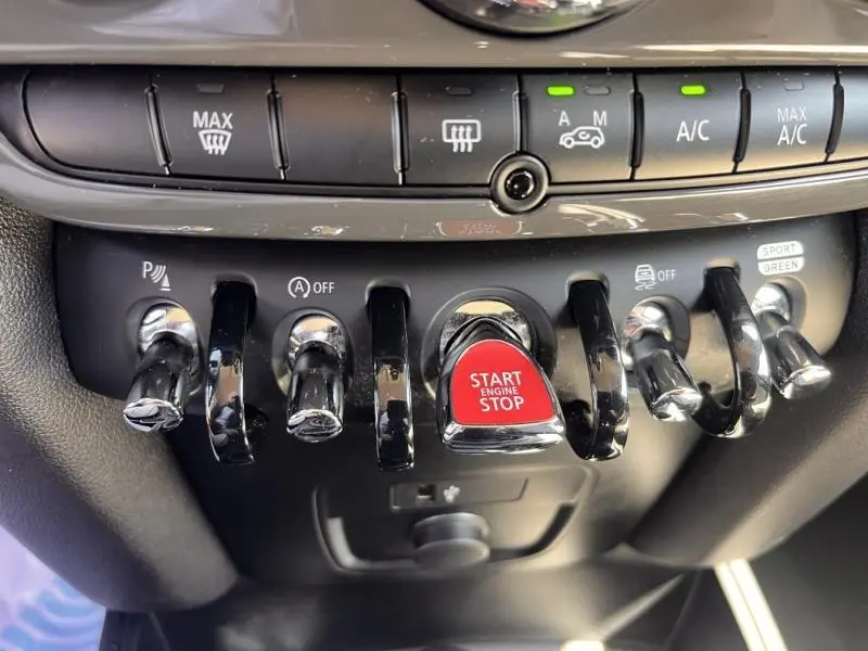 Gros plan sur les commandes centrales du tableau de bord de la MINI Countryman Cooper D, avec bouton rouge Start Engine Stop.