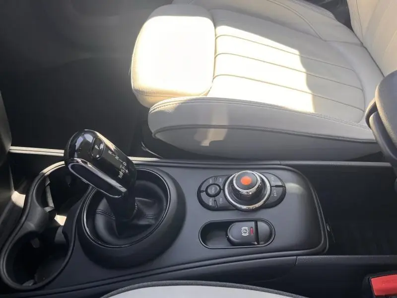 Vue rapprochée de la console centrale d'une MINI Countryman British Racing Green avec levier de vitesse automatique et sièges cuir clair.