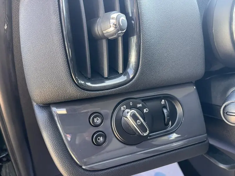 Gros plan sur la commande des phares et la sortie d'air côté gauche du tableau de bord gris foncé du MINI Countryman British Racing Green.