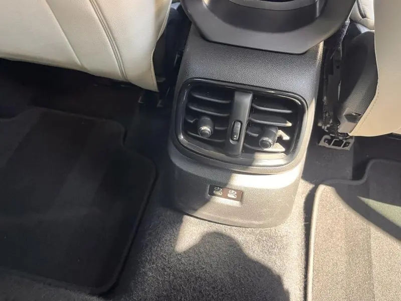Vue rapprochée des buses d’aération arrière et des ports USB situés entre les sièges avant en cuir clair du MINI Countryman British Racing Green.