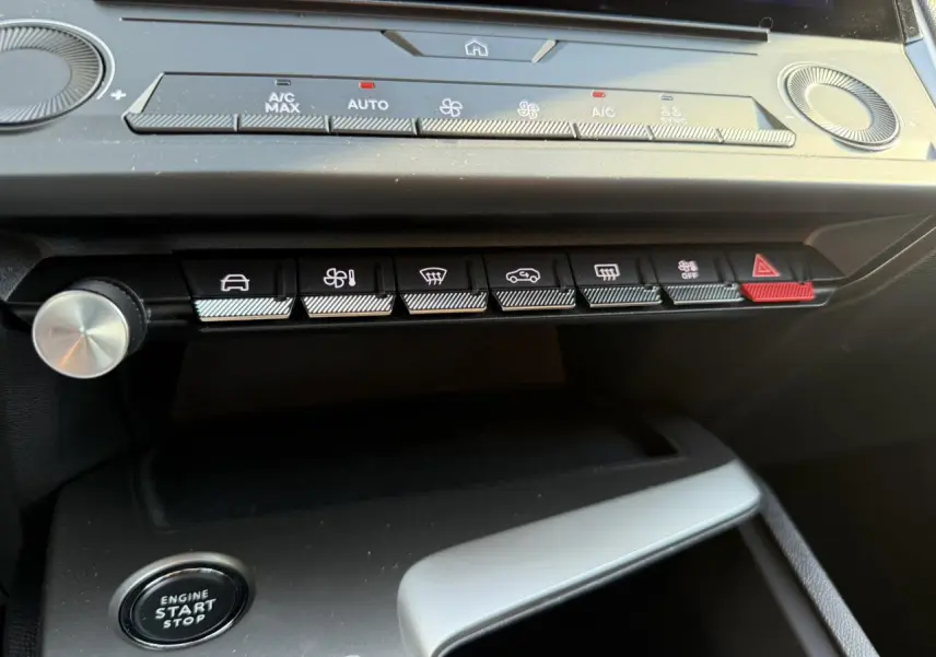 Vue rapprochée du tableau de bord de la Peugeot 308 2025 noir Perla, montrant les commandes climatisation et bouton start/stop.