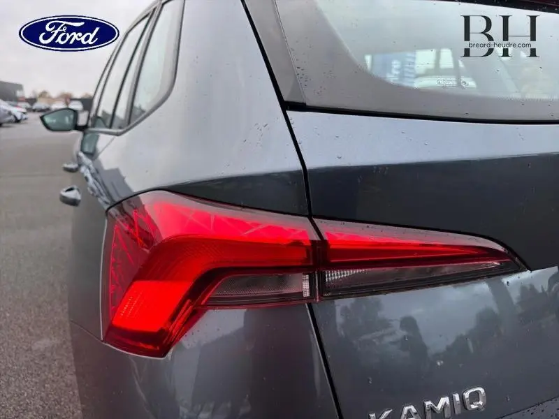 Feu arrière rouge en gros plan sur le côté gauche d’un Skoda Kamiq gris Météore, avec logo et badge visibles.