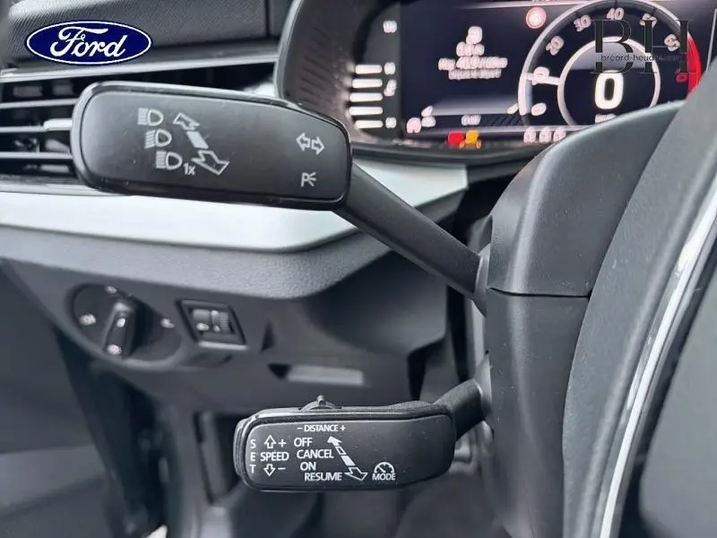 Gros plan sur les commandes au volant d’un Skoda Kamiq gris Météore, affichage numérique du tableau de bord visible.