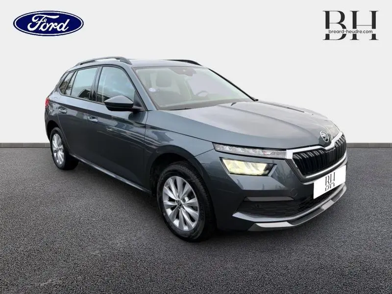 Vue 3/4 avant d'un Skoda Kamiq gris météore 2021 avec calandre chromée et feux LED allumés.