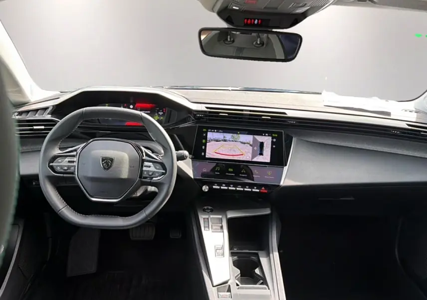 Vue intérieure avant de la Peugeot 408 Hybrid noire, avec volant cuir, écran tactile affichant la caméra de recul.