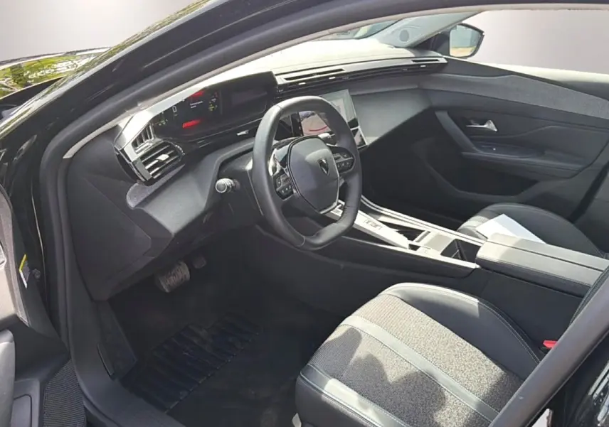 Intérieur avant droit d’une Peugeot 408 Hybrid 136 noire, volant cuir, console centrale moderne et sièges tissu/tep.