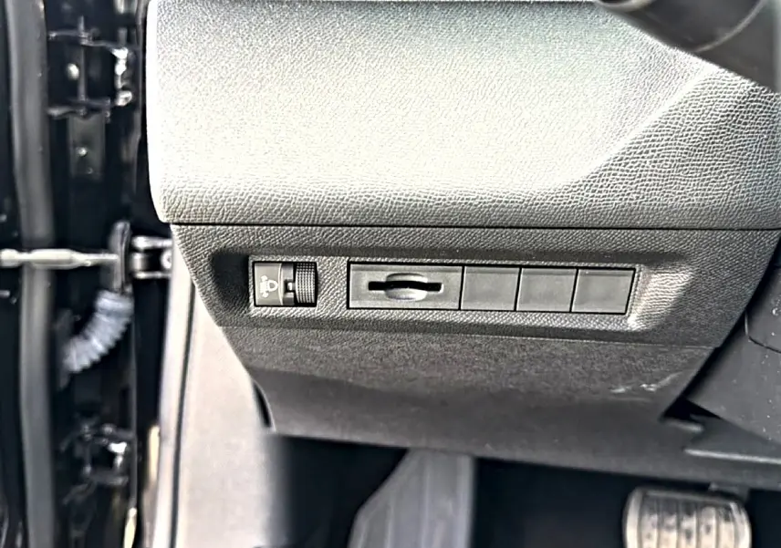 Détail des commandes d'éclairage côté gauche sous le tableau de bord d'une Peugeot 408 noir 2024.