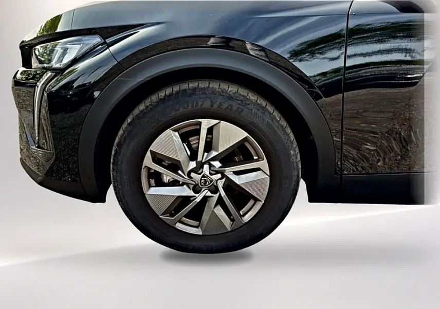 Gros plan sur la roue avant gauche et partie du pare-chocs avant noir brillant du Peugeot 408 Hybrid 136 allure 2024.