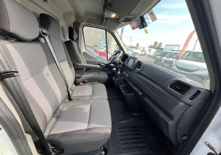 Vue intérieure côté passager du Renault Master blanc 2021, montrant les sièges gris et le tableau de bord noir.