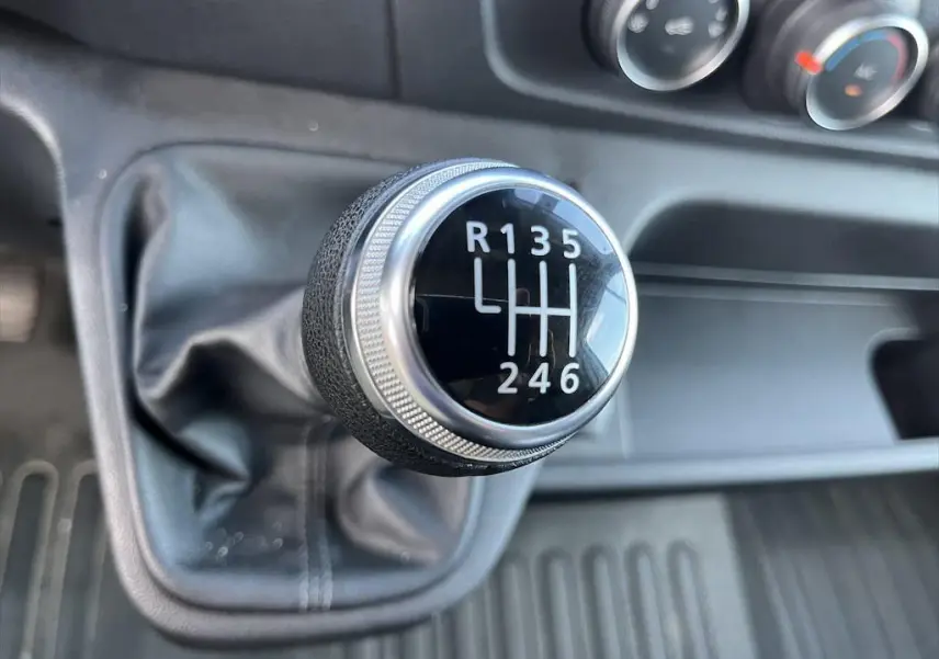 Gros plan sur le levier de vitesses manuel noir et argenté du Renault Master 2021, avec tableau de bord en arrière-plan.