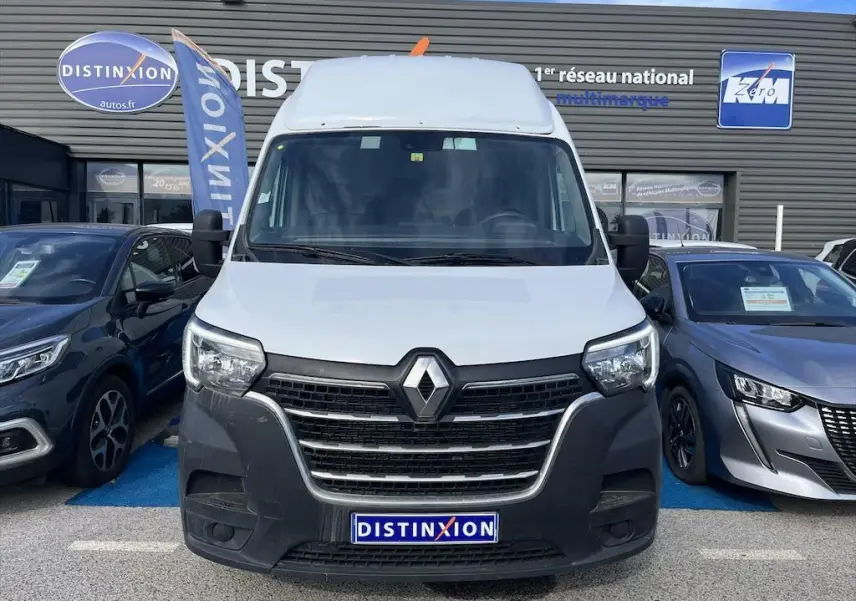Vue frontale d'un Renault Master blanc stationné devant un concessionnaire avec logo Distinxion visible.