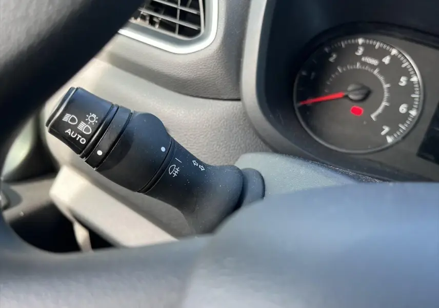 Gros plan sur la commande des phares et clignotants dans l'habitacle du Renault Master blanc, tableau de bord en arrière-plan.