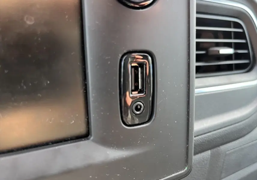 Gros plan sur la prise USB et la prise jack intégrées dans la console centrale noire du Renault Master blanc, côté droit.