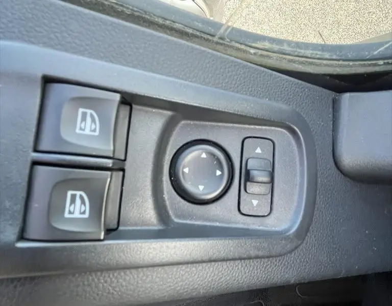 Gros plan sur les commandes de réglage des rétroviseurs et vitres côté conducteur du Renault Master blanc 2021.