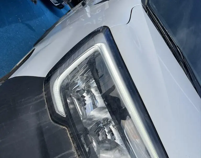 Gros plan sur le phare avant droit du Renault Master blanc, soulignant le capot et le rétroviseur noir.