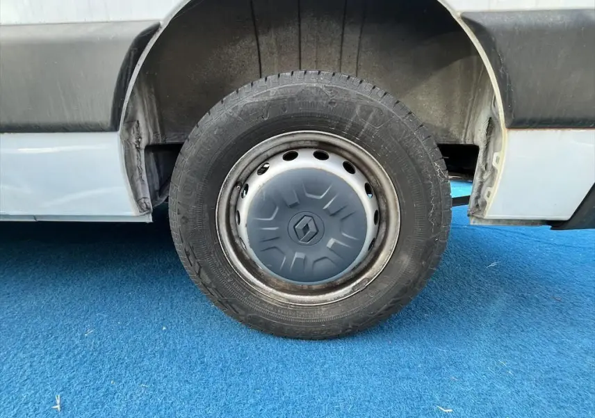 Gros plan sur la roue arrière droite d'un Renault Master blanc avec jante acier et enjoliveur gris.