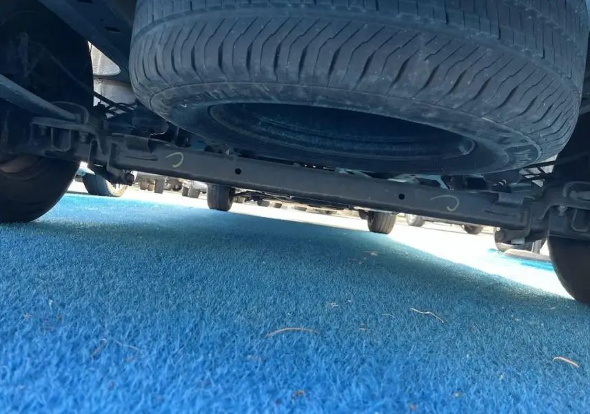 Vue en contre-plongée sous un Renault Master blanc, montrant la roue de secours suspendue et le châssis arrière.