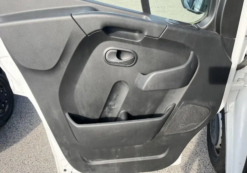 Gros plan sur la porte avant gauche noire du Renault Master blanc, montrant la poignée et le haut-parleur intégré.