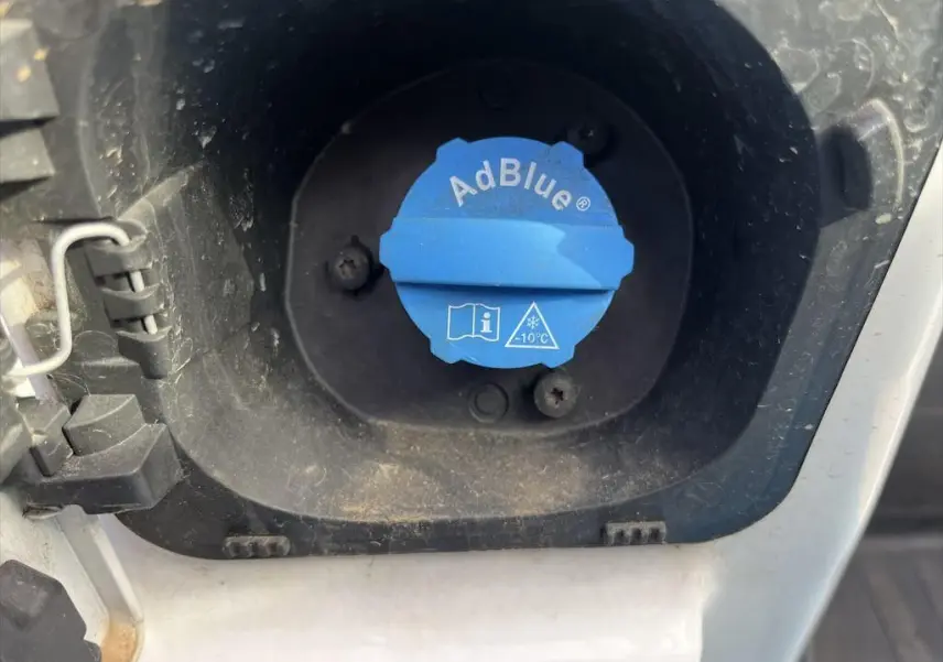 Bouchon bleu AdBlue en gros plan dans l'orifice de remplissage du réservoir d'un Renault Master blanc.