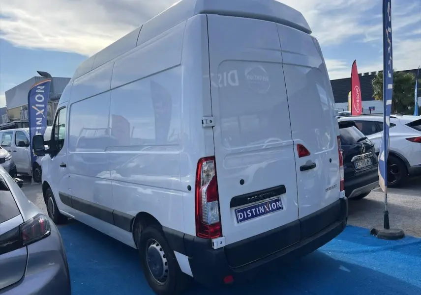 Renault Master blanc en vue 3/4 arrière droit sur un parking avec logo Distinxion sur la porte arrière.
