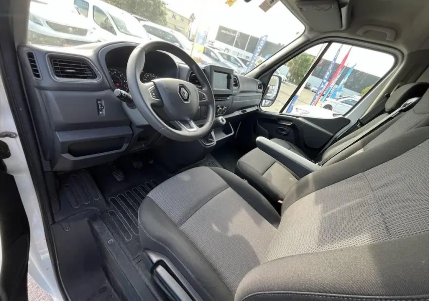Intérieur côté conducteur du Renault Master blanc 2021, montrant le tableau de bord et les sièges en tissu gris.