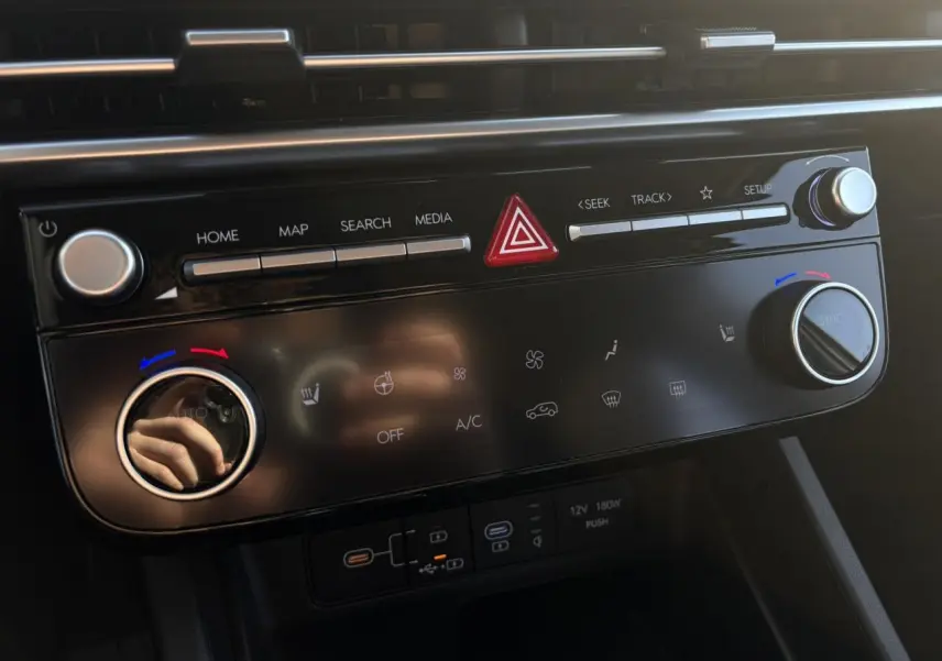 Tableau de bord du Hyundai Tucson 2025 en gros plan, avec commandes climatisation et multimédia noires brillantes.