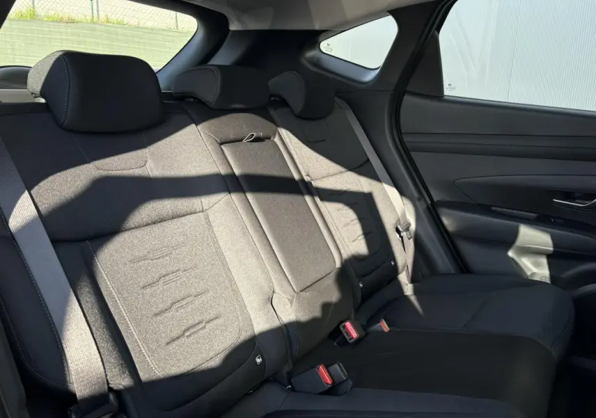 Vue côté droit de la banquette arrière noire du Hyundai Tucson 2025, avec appuie-têtes et ceinture de sécurité visibles.