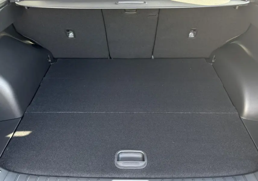 Coffre spacieux du Hyundai Tucson 2025 en Abyss Black, vue intérieure arrière avec plancher plat et revêtement noir.