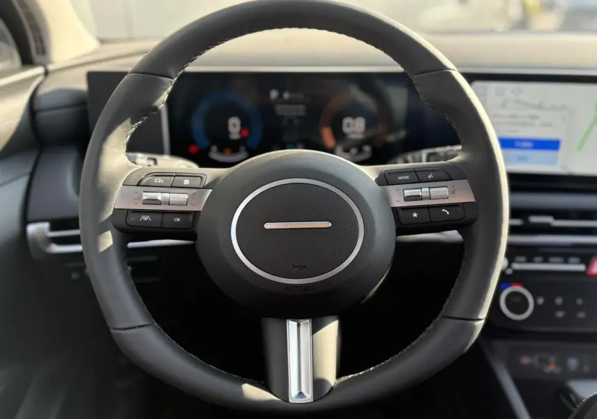 Volant cuir noir vu de face dans l'habitacle du Hyundai Tucson 2025 avec tableau de bord numérique et écran tactile.