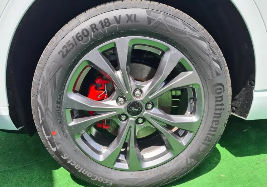 Gros plan sur la roue avant droite du Ford Kuga blanc glacier avec jante alliage 18 pouces et étrier de frein rouge.