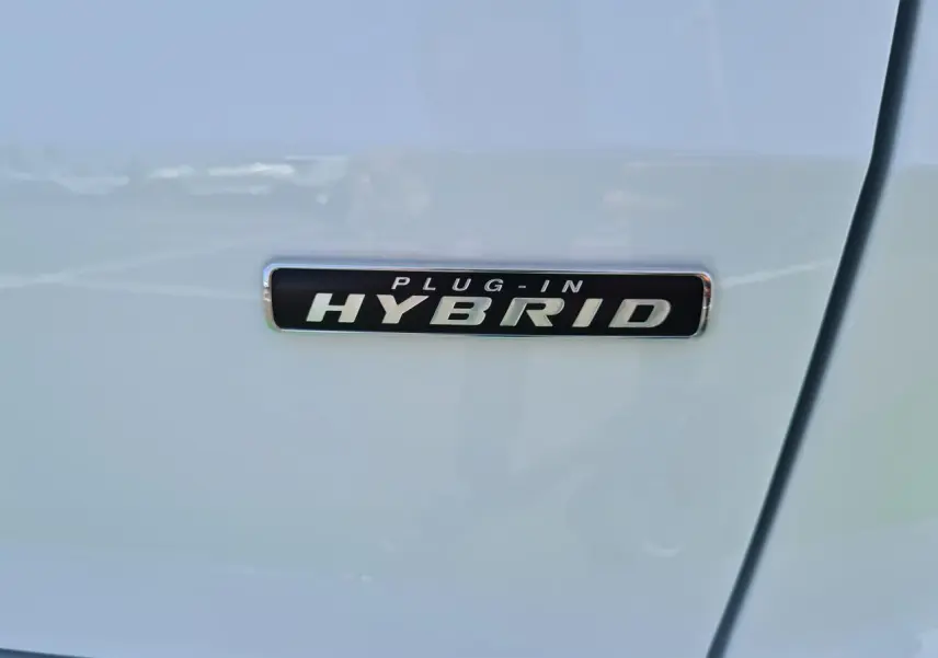 Gros plan sur l’inscription Plug-in Hybrid sur la porte blanche glacier d’un Ford Kuga hybride rechargeable.